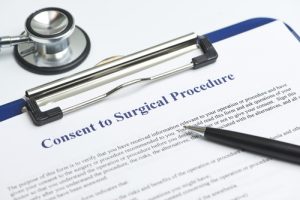Surgical consent form on clipboard with pen and stethoscope adjacent